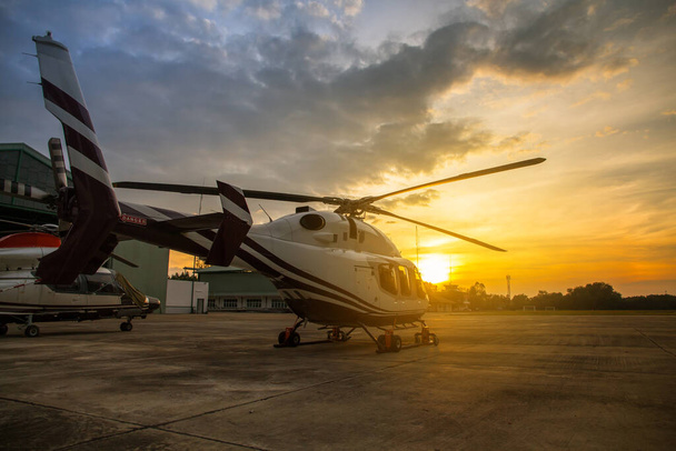 σιλουέτα του ελικοπτέρου στο χώρο στάθμευσης ή διάδρομο με φόντο την ανατολή του ηλίου, λυκόφως ελικόπτερο στην helipa - Φωτογραφία, εικόνα