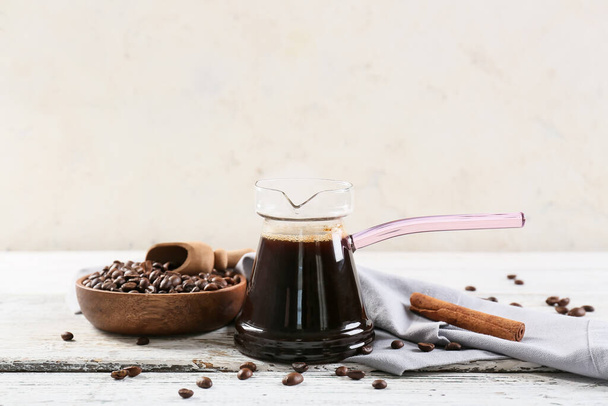Pot with delicious turkish coffee and plate with beans on light wooden background - Foto, imagen