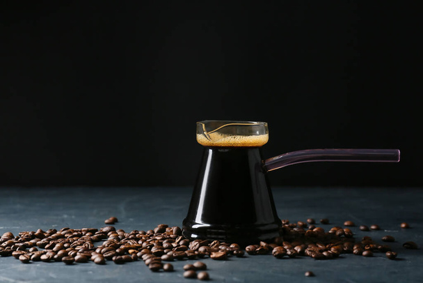 Kanne mit köstlichem türkischen Kaffee und Bohnen auf dunklem Hintergrund - Foto, Bild