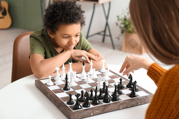 Cute African-American boy and his mother playing chess at home - Foto, Imagen