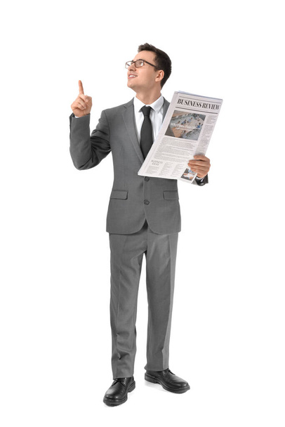 Jonge zakenman met krant wijst naar iets op witte achtergrond - Foto, afbeelding