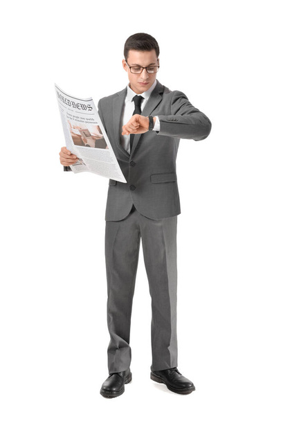 Jonge zakenman met krant kijken naar polshorloge op witte achtergrond - Foto, afbeelding