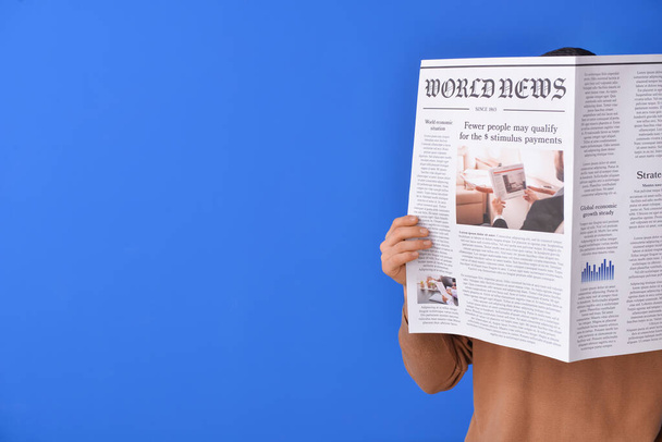 Young man reading newspaper on color background - Photo, image
