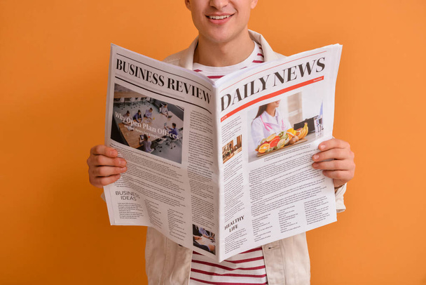 Young man reading newspaper on color background - Foto, Imagen