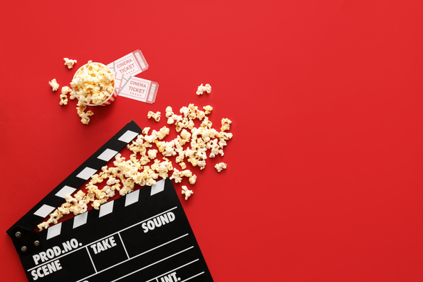 Tasty popcorn with cinema tickets and clapperboard on color background - Фото, зображення