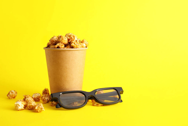 Paperi kuppi maukasta karamelli popcorn ja 3D lasit värillinen tausta - Valokuva, kuva