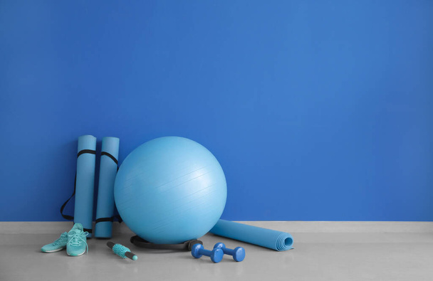 Set Sportgeräte mit Fitnessball und Schuhen in der Nähe der Farbwand - Foto, Bild