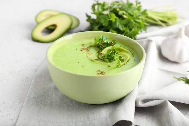 Bowl with green gazpacho, avocado and parsley on light background - 写真・画像