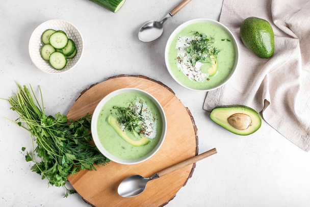 Bowls with green gazpacho and ingredients on light background - Foto, Imagem