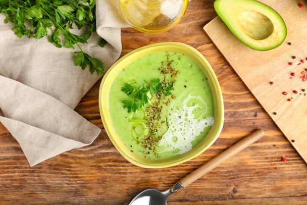Bowl with green gazpacho and ingredients on wooden background - Photo, Image