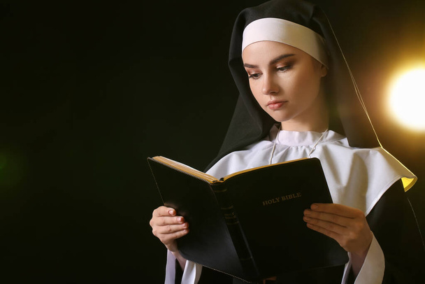 Junge Nonne mit Bibel auf dunklem Hintergrund - Foto, Bild