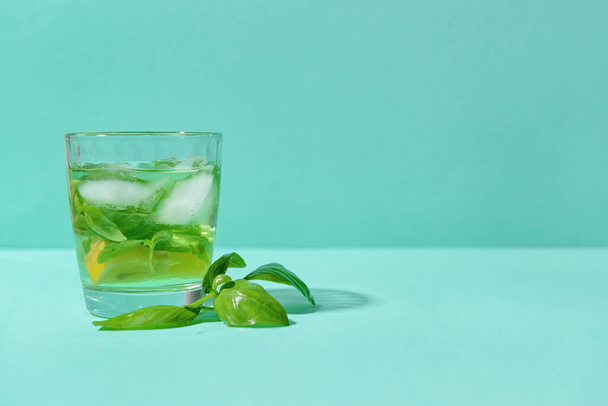 Glass of lemonade with basil on color background - Фото, изображение