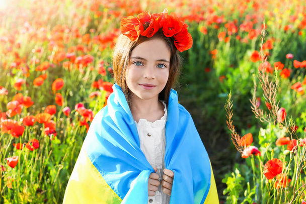 Little girl with Ukrainian flag in poppy field - 写真・画像