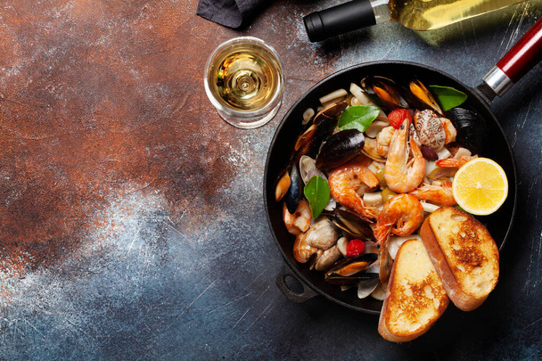 Mixed grilled seafood. Various roasted shrimps, mussels and shellfish in frying pan and white wine. Top view flat lay with copy space - Photo, Image
