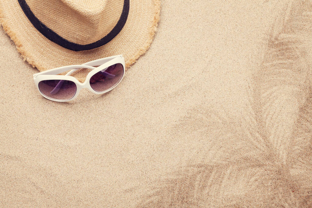 Viaje conceito de fundo de férias com óculos de sol e chapéu no fundo de areia. Vista superior com espaço de cópia. Depósito plano - Foto, Imagem