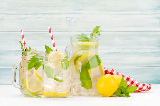 Fresh homemade lemonade with lemon and mint in pitcher and glass jar - Photo, Image