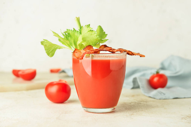 Glass of bloody mary cocktail garnished with bacon and tomatoes on light background - Photo, Image