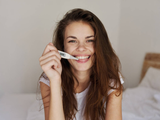 femme gaie tenant un thermomètre dans sa bouche sourire test positif - Photo, image