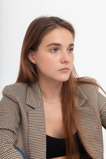 jeune femme caucasienne attrayante avec de longs cheveux bruns en costume veste au studio - Photo, image