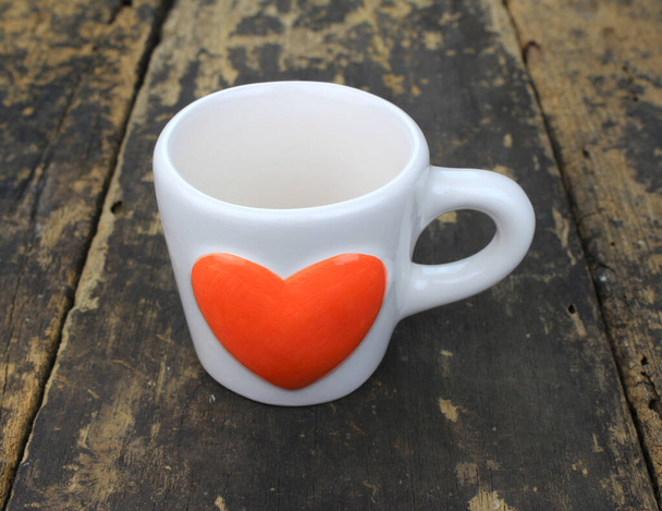 orange heart coffee cup on wooden table - Photo, Image