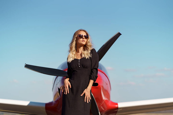 Czarująca kobieta pozująca na tle samolotu - Zdjęcie, obraz