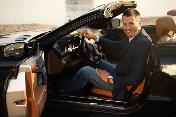 Young businessman in luxury convertible car outdoors - Fotografie, Obrázek