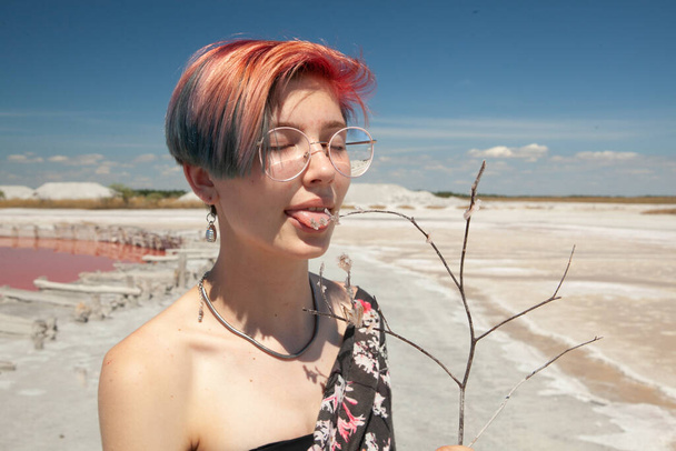 das Mädchen schmeckt das Salz aus dem rosa See und berührt es mit der Zunge - Foto, Bild