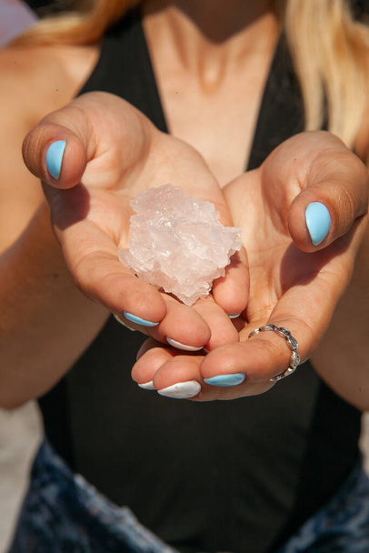 vrouw met natuurlijke zout kristallen in haar handen in de zomer - Foto, afbeelding