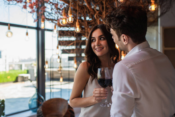 smiling man and woman holding glasses of red wine in restaurant  - Photo, Image
