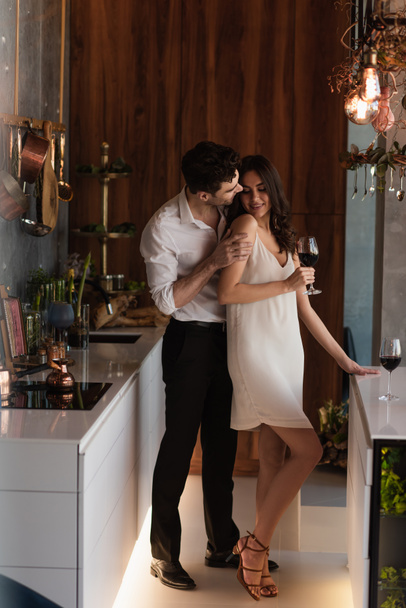 muž svést usmívající se přítelkyně ve skluzu šaty se sklenkou vína - Fotografie, Obrázek