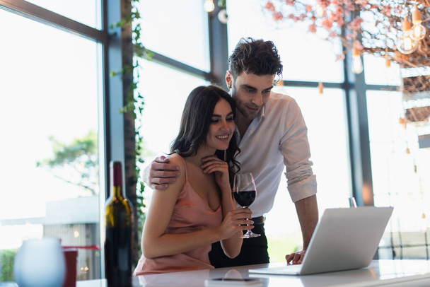 happy couple watching movie on laptop near bottle of wine - Photo, Image