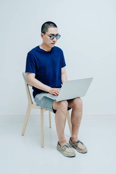 Молодые люди в повседневных футболках работают с ноутбуками - Фото, изображение