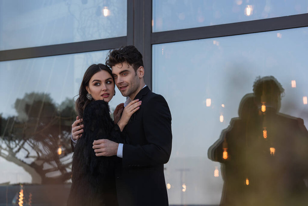 donna in pelliccia sintetica giacca abbracciare uomo elegante in tuta all'aperto  - Foto, immagini