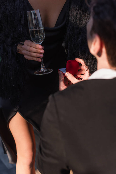 bijgesneden beeld van man die aanzoek doet aan vrouw met glas champagne  - Foto, afbeelding