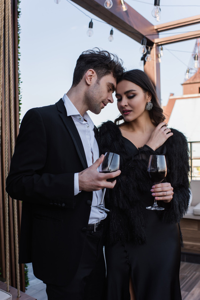 elegant woman and man holding glasses of wine on terrace  - Photo, Image