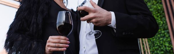 μερική άποψη του ζεύγους που κατέχουν ποτήρια του κόκκινου κρασιού, πανό - Φωτογραφία, εικόνα