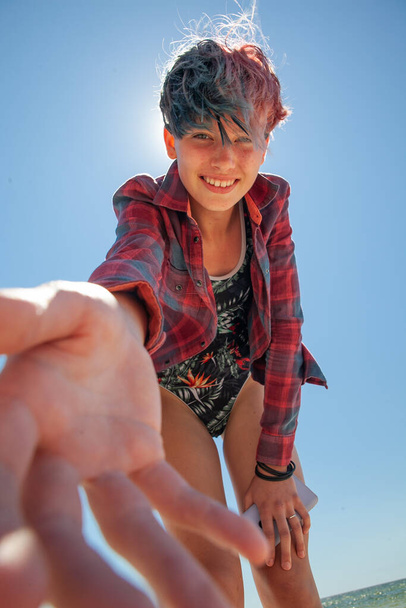 Mädchen in Badeanzug und Hemd vor blauem Himmel streckt die Hand aus - Foto, Bild