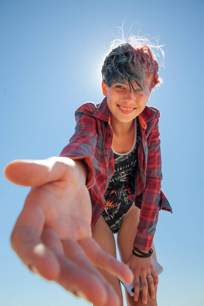 Девушка в купальнике и рубашке на фоне голубого неба протягивает руку - Фото, изображение