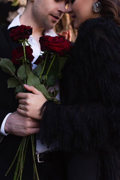 bijgesneden uitzicht van man met rode rozen in de buurt van vrouw  - Foto, afbeelding