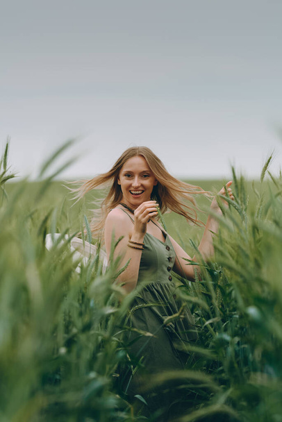 Young woman in a wheat field rejoices, laughs, enjoys life and summer. Wheat field. Beautiful Nature Landscape under Sunlight. Healthy lifestyle Concept. Image with noise, film grain - Foto, Bild