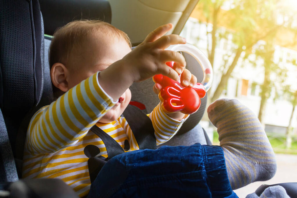 Happy baby sitting in car seat, playing.  - Foto, imagen