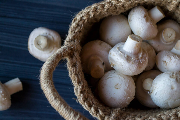 The champignons in a basket on a wooden table. - Foto, imagen