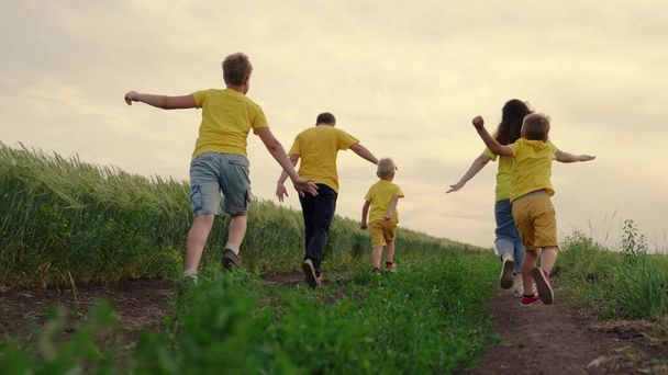 Sons, children, mom, dad run, play, rejoice, enjoy nature in summer. Family teamwork. Happy family team, running together in field, happily waving their hands. Group of people of different ages - Photo, Image