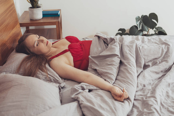 Beautiful girl in red pajama sleeping in bed - Fotografie, Obrázek