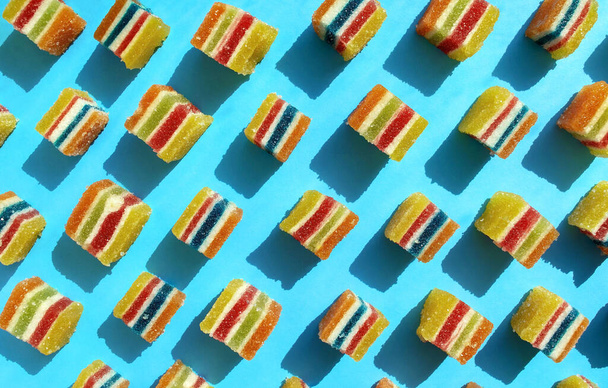 Colorful square jelly candies pattern on a bright blue background. Yellow, pink, red, orange, white, green square shaped marmalade pattern. - Photo, Image