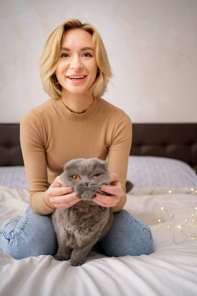 Young woman and cat on bed in the room - 写真・画像