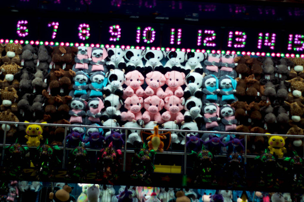 Rijen van kleurrijke diverse knuffeldieren speelgoed prijzen op carnaval spel in pretpark 's nachts. - Foto, afbeelding
