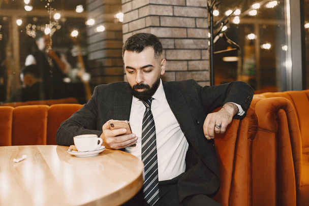 Stylish businessman with coffee sitting at the table - Zdjęcie, obraz