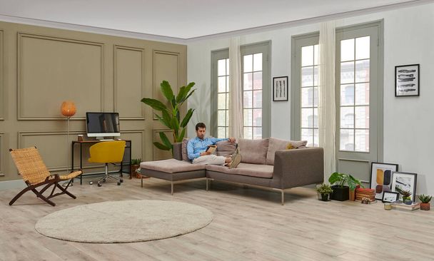 Mann liest ein Buch im dekorativen Wohnzimmerstil, grauer Sofa-Arbeitstisch Hintergrund Home Design. - Foto, Bild