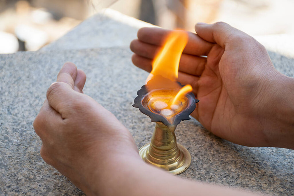 Foto stock di canfora in fiamme conservata in canfora titolare per presentare rituali, l'uomo che tiene la mano vicino alla fiamma per proteggere la fiamma per l'aria a Bangalore Karnataka India. - Foto, immagini